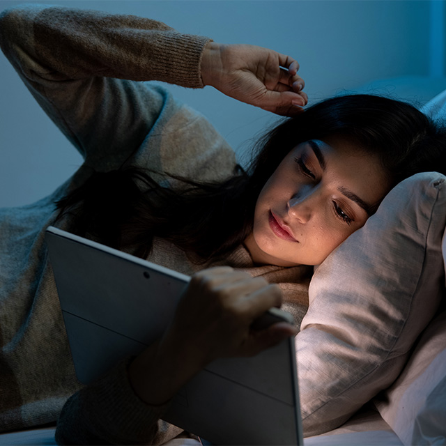 woman viewing tablet in bed
